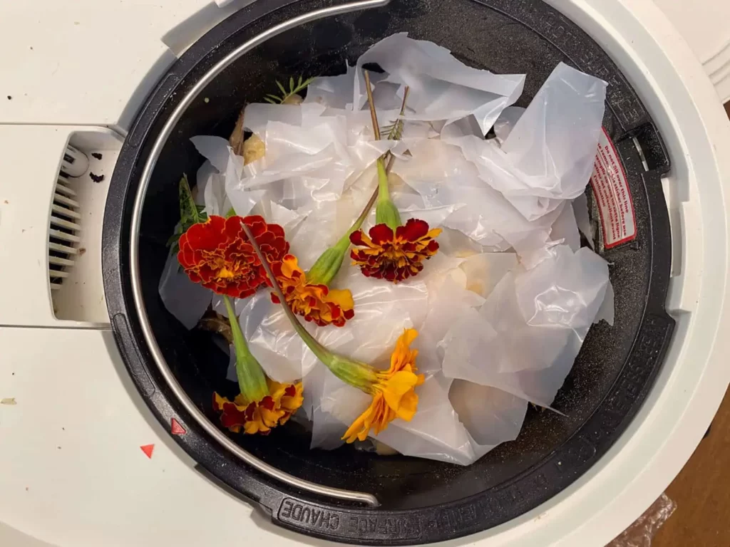 déchets alimentaires et plastique dans le seau du composteur Lomi
